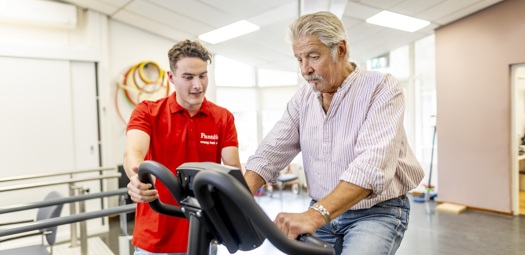 Fysiotherapeut met patiënt op hometrainer